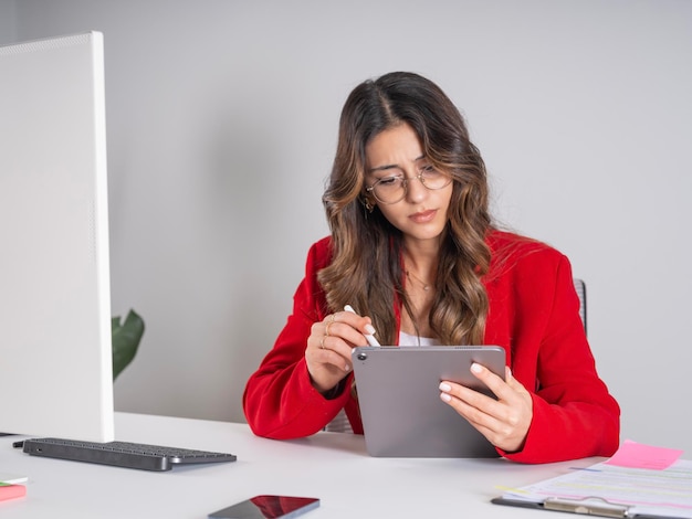 デジタル筆を使ったタブレットを握っている眼鏡をかぶった真っ白な茶色の女性ビジネスマン