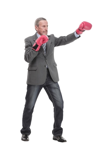 Serious caucasian elderly man in business formal outfit in boxing gloves hitting