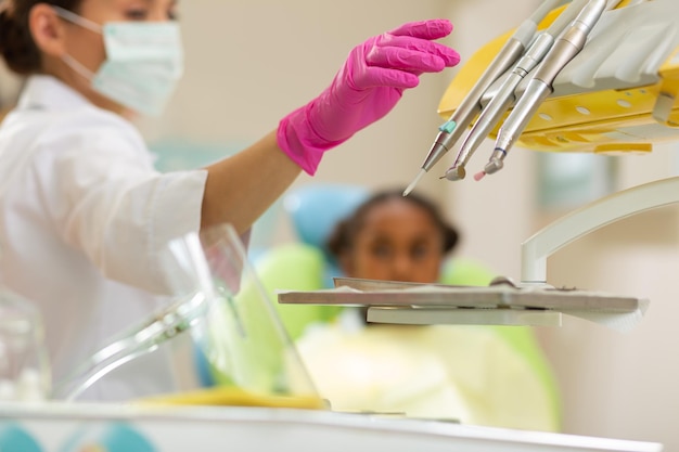 Serious Caucasian female dentist reaching for dental instruments