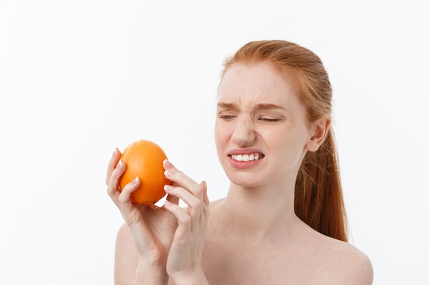 Serious Caucasian woman with orange on hand