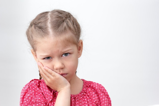 Serious child holding hand on cheek feeling ache