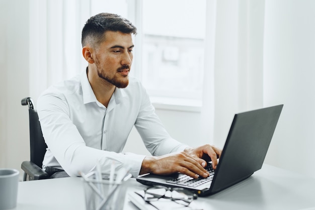 Serious concentrated disabledman in wheelchair using his laptop