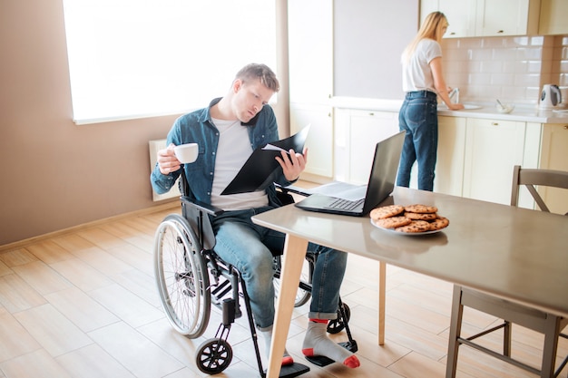 Giovane studente serio concentrato con inclusività e disabilità. studiare e parlare al telefono. tieni la tazza di caffè. giovane donna che lava i piatti nel lavandino. lavorare insieme.