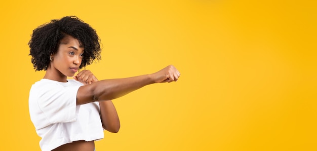 Serious confident millennial african american curly woman in white tshirt fighting punching