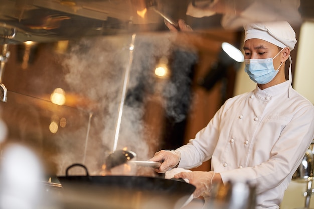 キッチンで蒸し暑い食事を準備する真面目な料理人