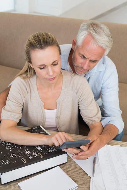 Serious couple calculating their bills at the couch