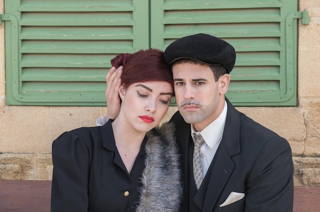 serious couple sitting against wall