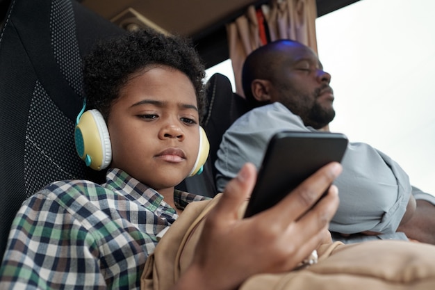 Serious cute little boy looking at smartphone screen