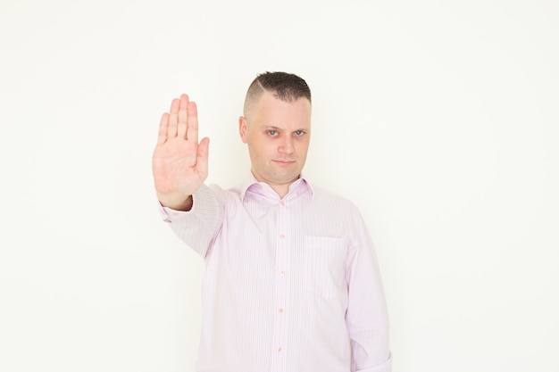 Serious displeased businessman showing stop gesture and looking at camera.