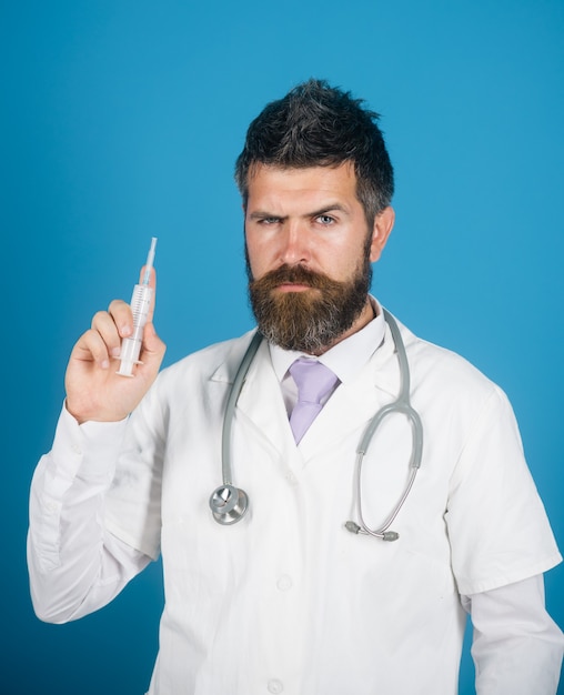 Serious doctor hold syringe with vaccine. Bearded physician in medical gown ready to make injection.
