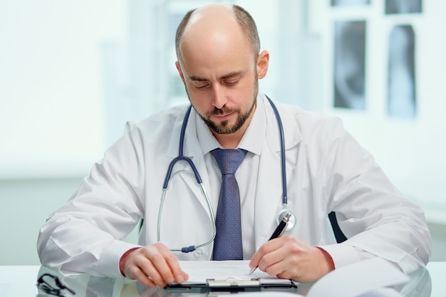 Serious doctor making notes in a notebook