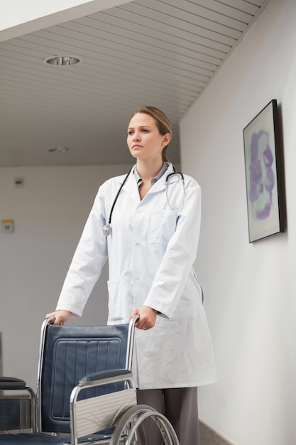 Serious doctor pushing a wheelchair