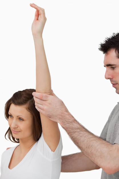 Serious doctor raising the arm of a woman