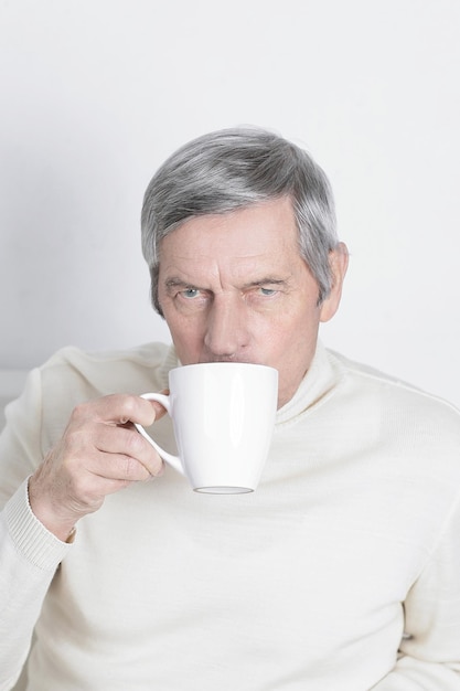 白で隔離された一杯のコーヒーを持った深刻な老人