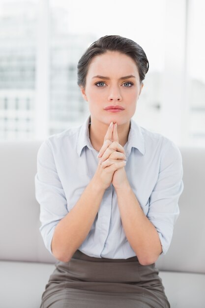 Serious elegant young woman sitting at home