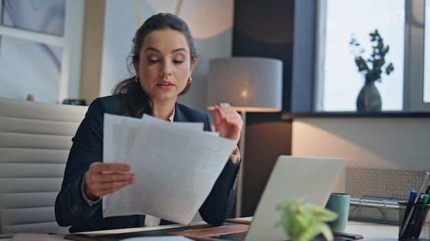 Serious employee reading papers in office closeup tired manager closed laptop