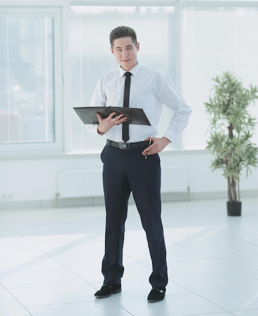 Serious employee with documents standing in the office