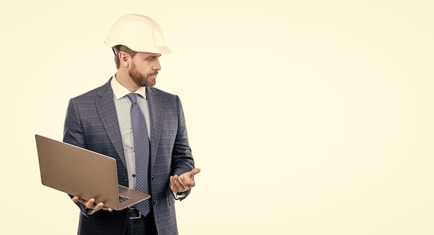 Serious engineer man in hardhat and suit use laptop computer for constructing engineering