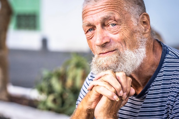 Serious expression of man with blue eyes 75 year old senior man with white hair looking into the camera