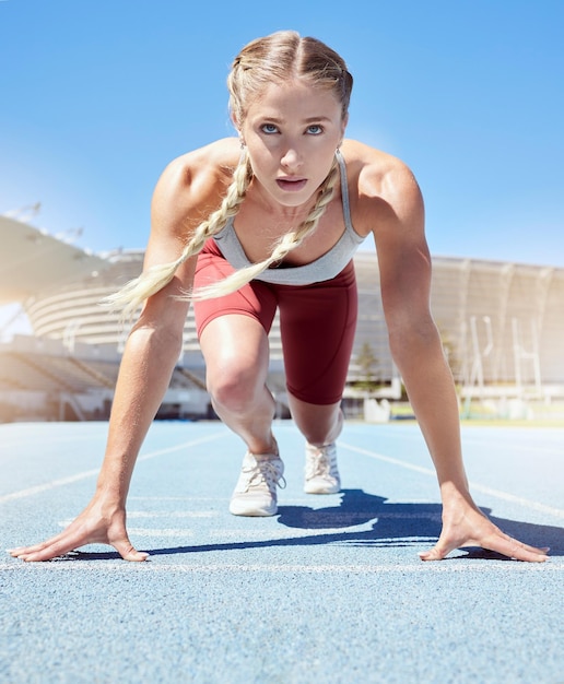 スタジアムでの陸上競技のスタートラインにいる真面目な女性アスリートスプリントラインまたはスターティングブロックで走り始める準備ができているスポーツウーマンに心身ともにフィット