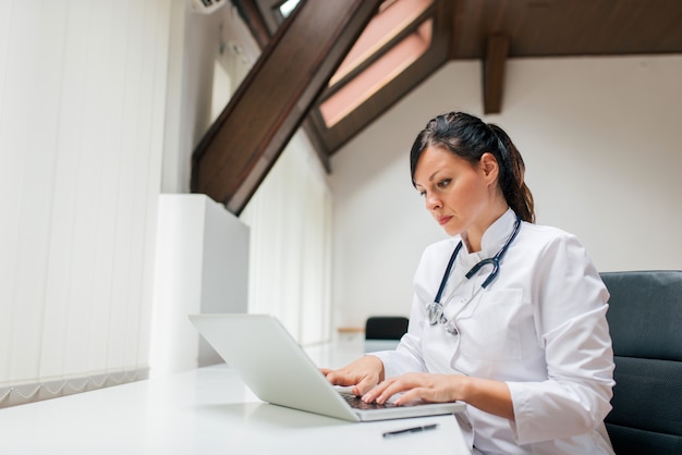 Photo serious female doctor working on laptop.