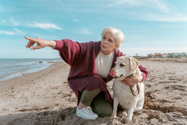 Serious focused senior woman sitting on her haunches and teaching her dog the Fetch command