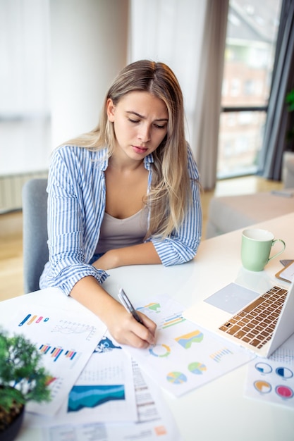 Serious frowning woman sit at workplace desk looks at laptop screen read email feels concerned Bored unmotivated tired employee problems difficulties with app