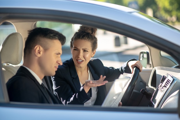 深刻なジェスチャー女性の運転と車の中で男