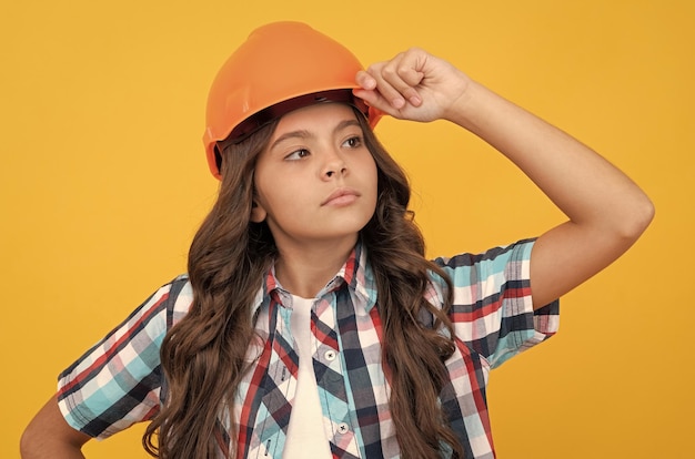 Serious girl in protective hard hat child wear helmet for building protection and safety