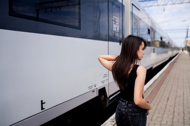 Ragazza seria con la schiena sul lato di un treno