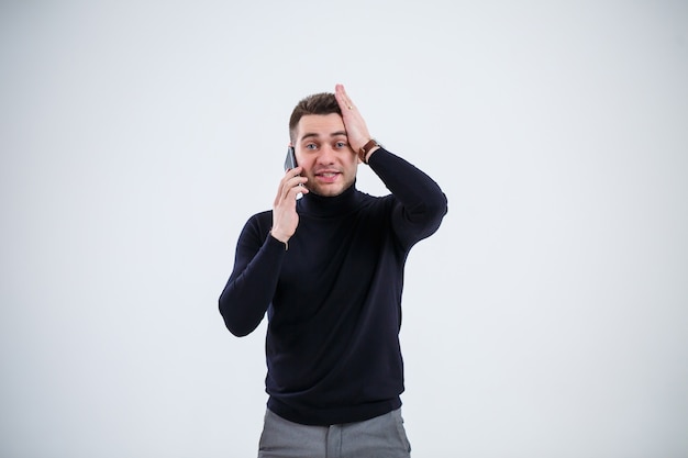 Serious guy businessman in black clothes finds out important questions by phone. Working day concept