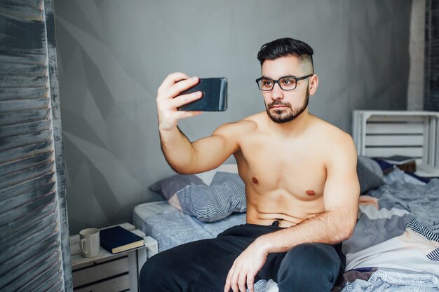 Serious guy doing selfie in bed in the morning