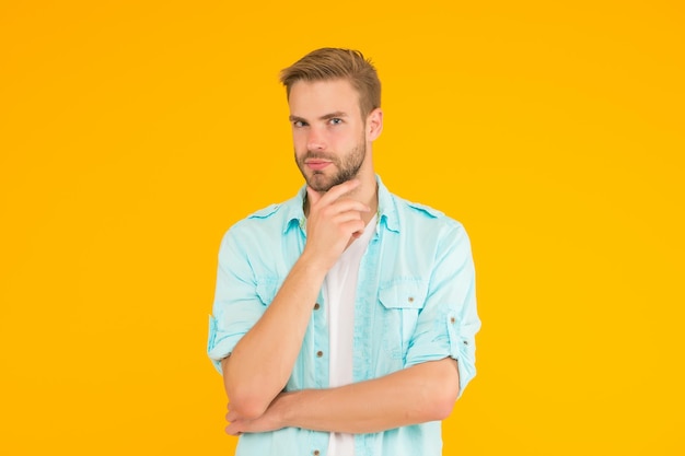 Serious guy with bristle wear denim style outfit over yellow background facial care