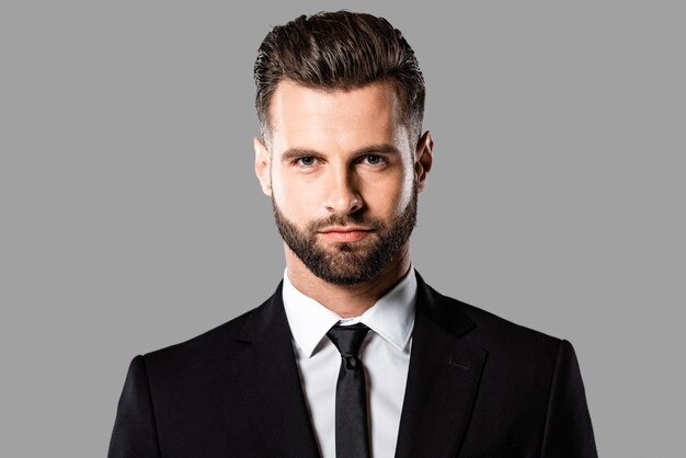 Serious handsome businessman in black suit isolated on grey