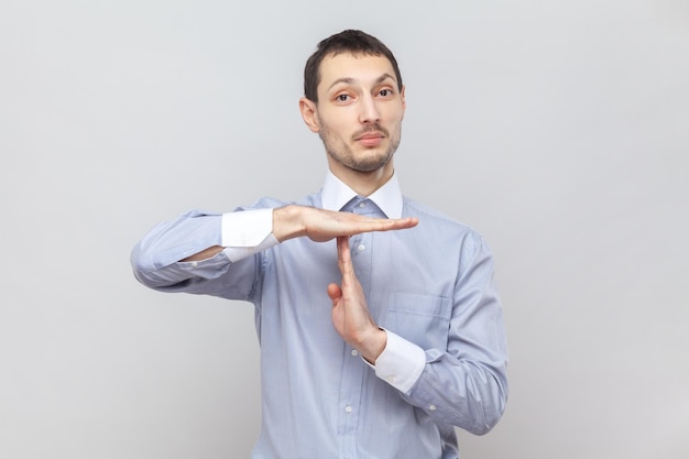 Serious handsome man standing showing timeout gesture looking at camera looking at camera