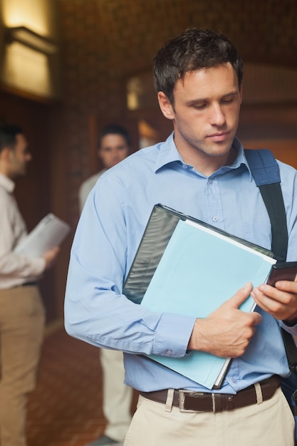 Foto studente maturo bello serio che utilizza il suo smartphone