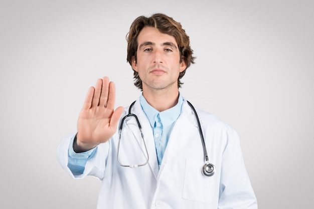 Serious male doctor gesturing stop with hand healthcare concept