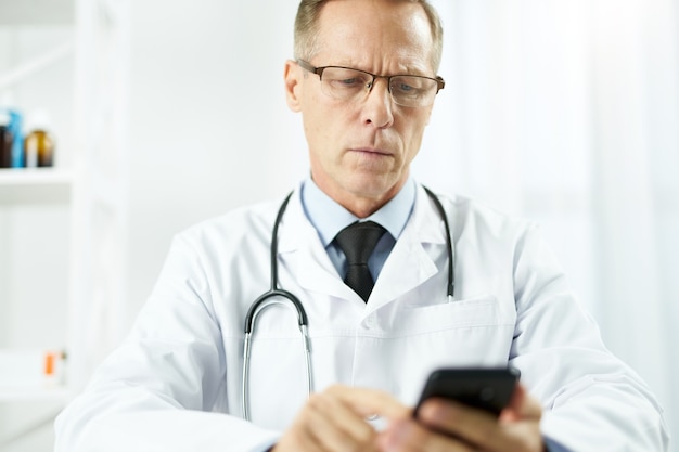 Serious male doctor using mobile phone at work