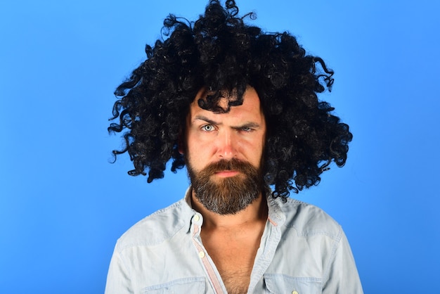 Photo serious man in curly wig serious bearded man portrait of serious man isolated wig colorfull hair