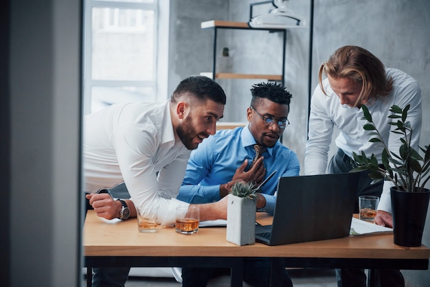 Serious man fully concentrated. Multiracial business people with laptop solving the company issues