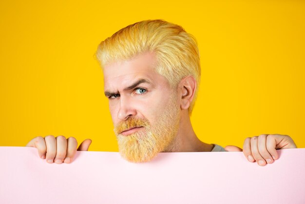 Serious man holding empty placard board for media banner sale surprised bearded man holding empty ye