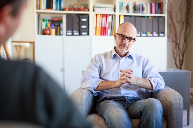 Photo serious man looking at friend while sitting on sofa