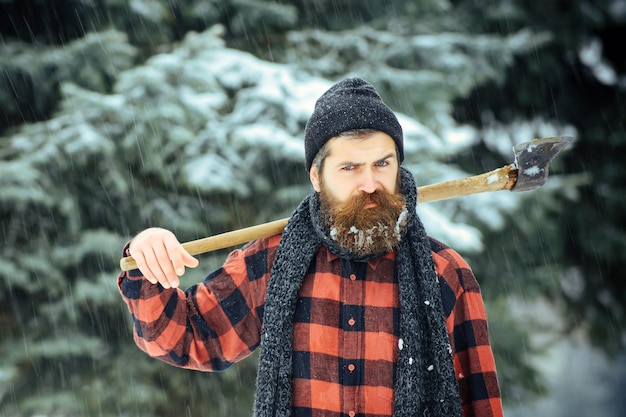 Serious man lumberjack with axe outdoor in winter