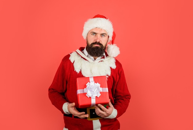 Serious man in santa costume holds present gift box wish you merry christmas santa claus holds