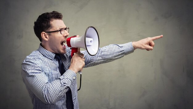 Serious man shouting into megaphone and pointing away