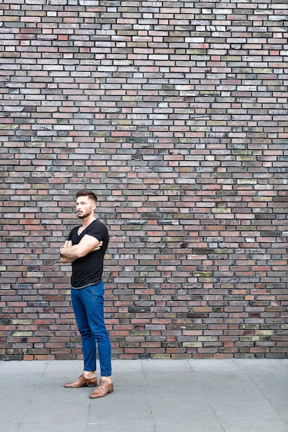 Serious man standing at brick wall