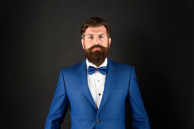 Serious man in tuxedo bowtie butler in formalwear on black\
background male formal fashion