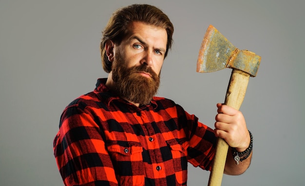 Serious man with axe bearded lumberjack with ax male in checkered shirt with hatchet logger tool