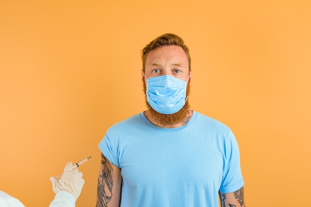 Serious man with beard tattoo and mask for covid is ready for the virus vaccine