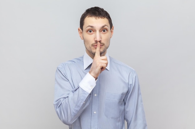 Serious man with finger near lips showing shh gesture asking to keep silence during lesson